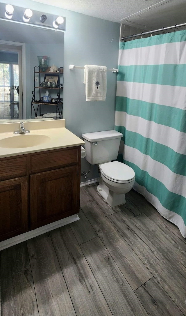 bathroom with toilet, wood finished floors, curtained shower, a textured ceiling, and vanity