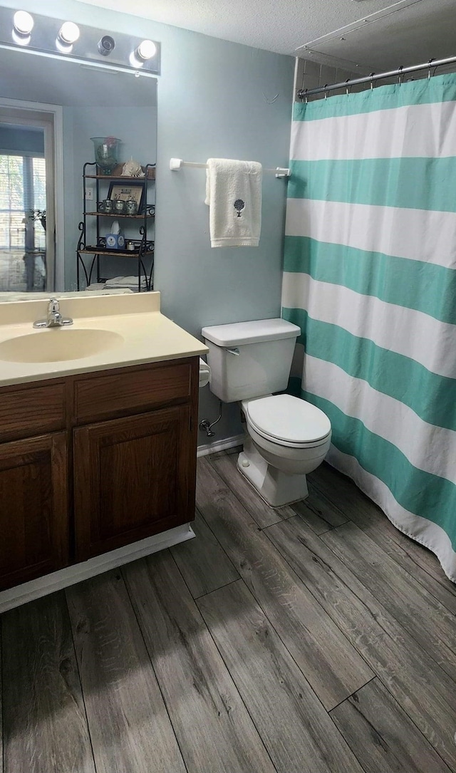 344 W Harwood Rd Unit A, Hurst, TX 76054 - full bathroom featuring toilet, vanity, wood finished floors, a textured ceiling, and a shower with shower curtain