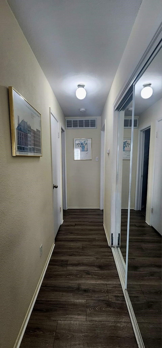 hall with wood finished floors, visible vents, and baseboards