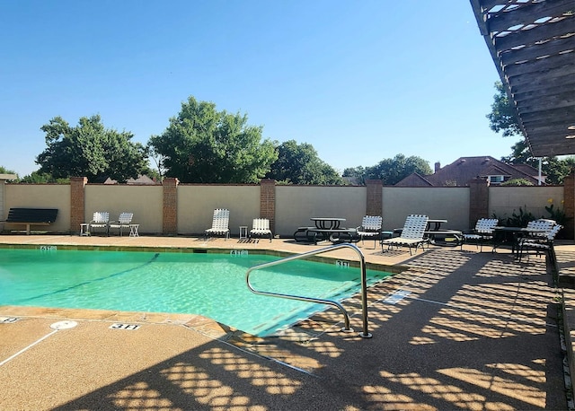 community pool with a patio and fence