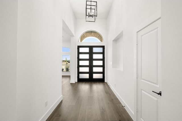 foyer with a towering ceiling, a chandelier, and dark hardwood / wood-style floors