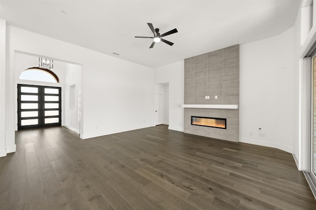 unfurnished living room with dark hardwood / wood-style flooring, ceiling fan with notable chandelier, and a tiled fireplace