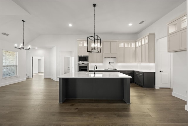 kitchen featuring decorative light fixtures, white cabinetry, stainless steel appliances, sink, and a kitchen island with sink