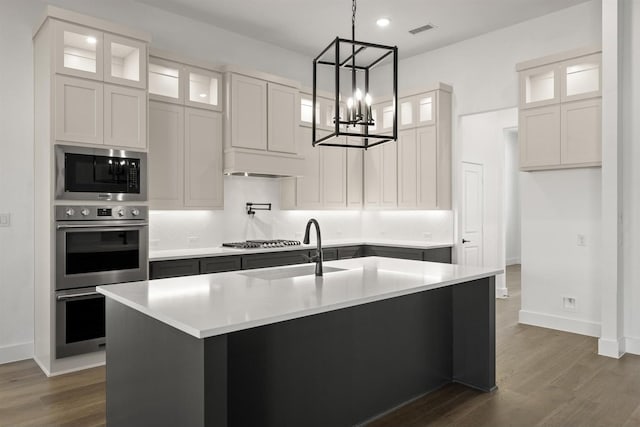 kitchen with sink, white cabinetry, an island with sink, stainless steel appliances, and dark hardwood / wood-style flooring