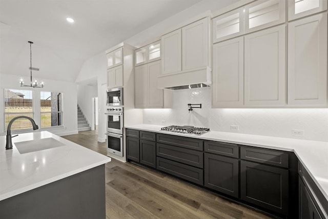 kitchen featuring white cabinetry, appliances with stainless steel finishes, lofted ceiling, a chandelier, and sink