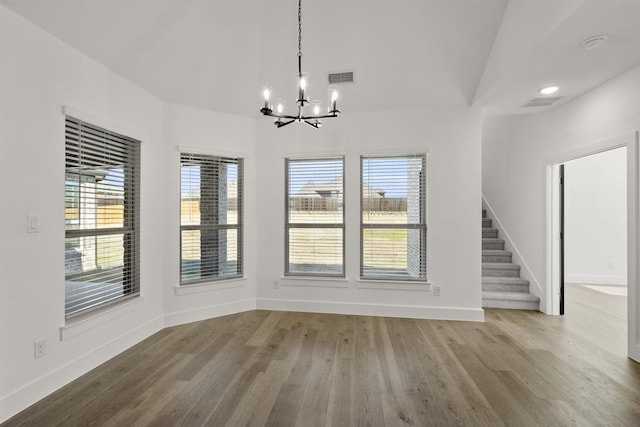 unfurnished dining area with hardwood / wood-style flooring and a notable chandelier