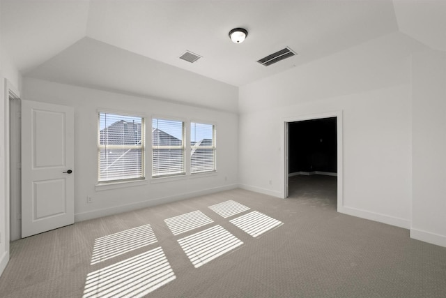 carpeted empty room featuring lofted ceiling