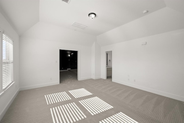 carpeted empty room with vaulted ceiling