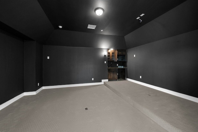 carpeted cinema room with sink and vaulted ceiling