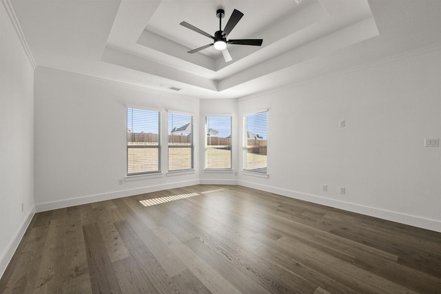 empty room featuring ceiling fan, dark hardwood / wood-style floors, ornamental molding, and a raised ceiling