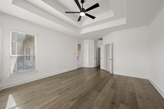 unfurnished room featuring ceiling fan, a tray ceiling, dark hardwood / wood-style floors, and crown molding