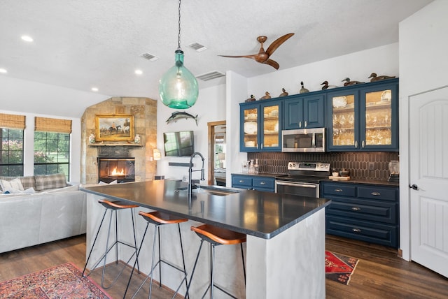 kitchen featuring sink, a kitchen bar, blue cabinetry, appliances with stainless steel finishes, and dark hardwood / wood-style flooring