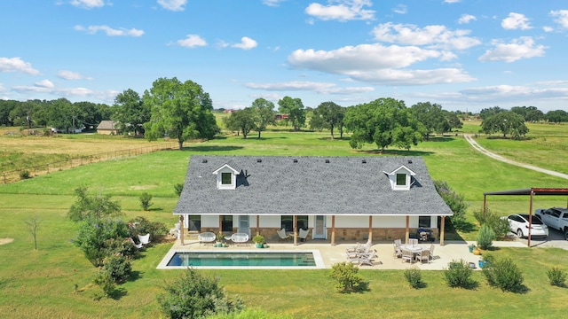 rear view of house featuring a patio area, a lawn, and a rural view