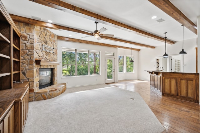 unfurnished living room featuring beam ceiling, ceiling fan, light wood-type flooring, a fireplace, and sink