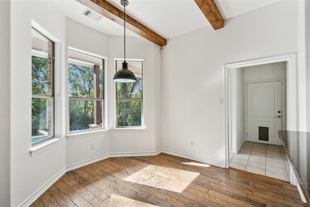 unfurnished dining area featuring beam ceiling and hardwood / wood-style flooring