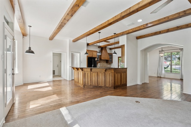 kitchen with black fridge, light hardwood / wood-style floors, pendant lighting, beam ceiling, and premium range hood