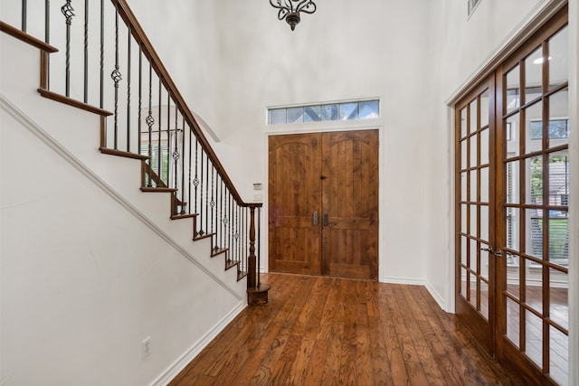 foyer entrance featuring a towering ceiling, french doors, dark hardwood / wood-style floors, and plenty of natural light