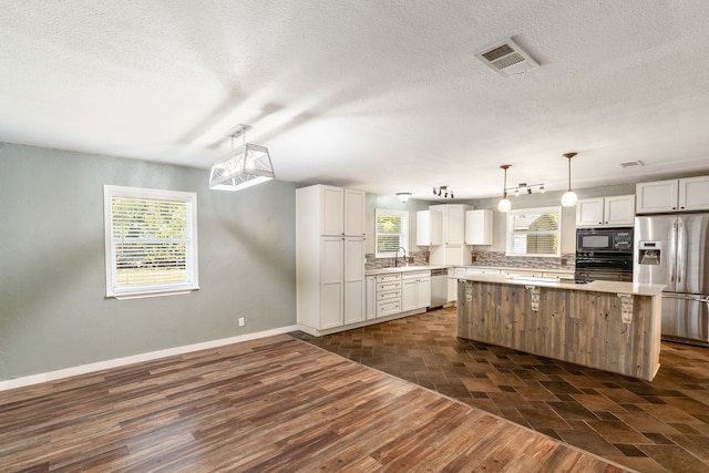 kitchen featuring black appliances, sink, a center island, decorative light fixtures, and white cabinets