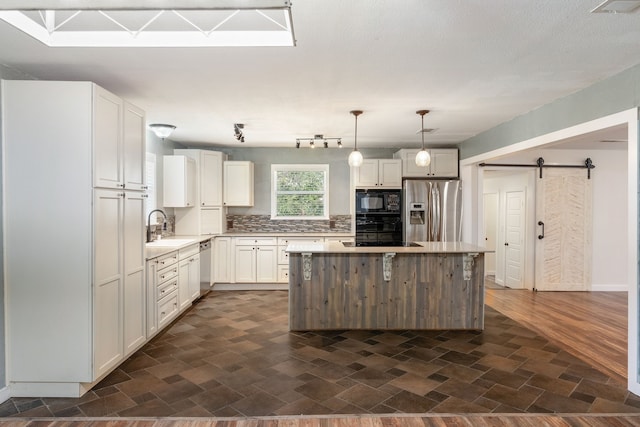 kitchen with a kitchen island, hanging light fixtures, black appliances, a barn door, and dark hardwood / wood-style flooring