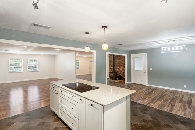 kitchen featuring dark hardwood / wood-style floors, black electric cooktop, a wood stove, decorative light fixtures, and white cabinetry