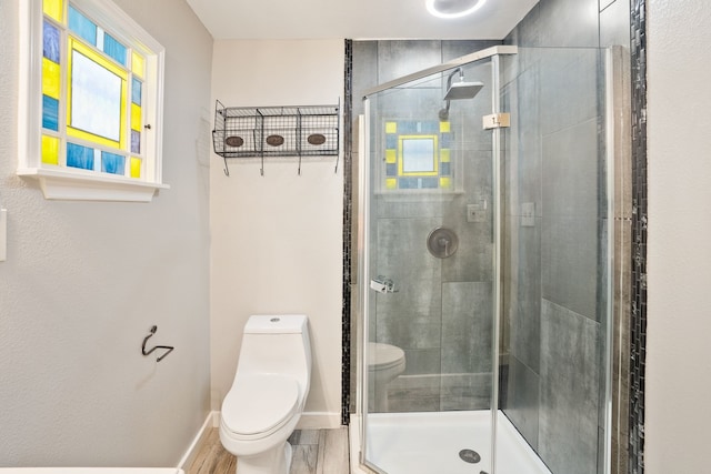 bathroom featuring toilet, wood-type flooring, and a shower with door