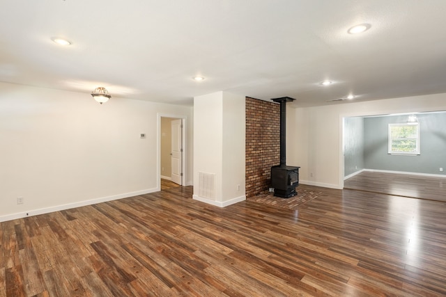 unfurnished living room with a wood stove and dark hardwood / wood-style flooring