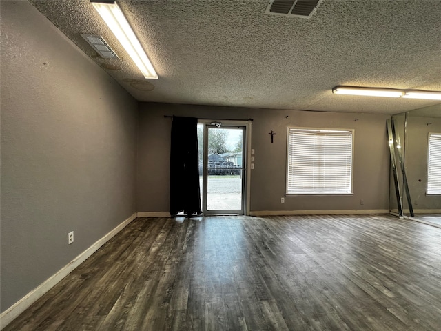 unfurnished room with a textured ceiling and dark hardwood / wood-style floors