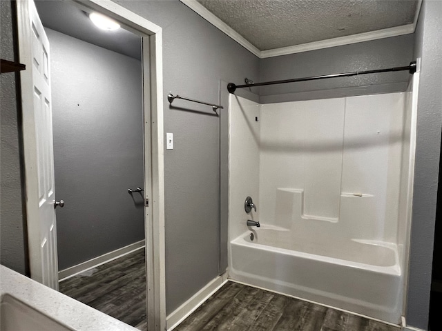 bathroom featuring shower / bathing tub combination, hardwood / wood-style floors, a textured ceiling, and crown molding