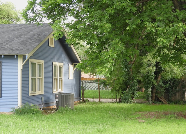 view of side of home with central air condition unit and a yard