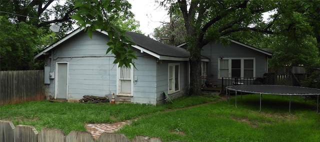 back of house featuring a yard and a trampoline