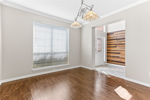 entrance foyer with ornamental molding, wooden walls, wood-type flooring, and a textured ceiling