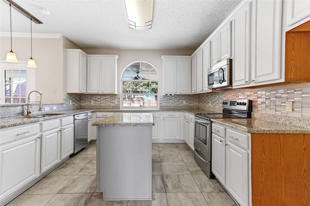 kitchen featuring appliances with stainless steel finishes, white cabinetry, light stone countertops, sink, and a center island