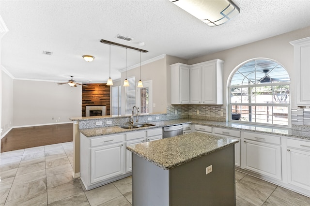 kitchen with kitchen peninsula, white cabinets, a textured ceiling, sink, and a center island