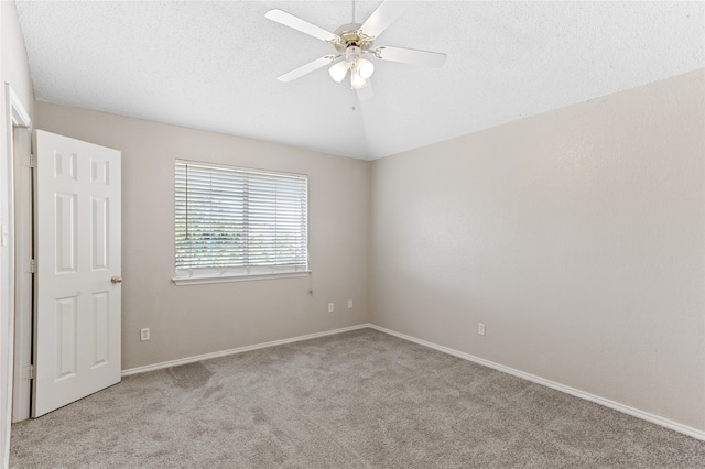 carpeted spare room with ceiling fan, a textured ceiling, and vaulted ceiling