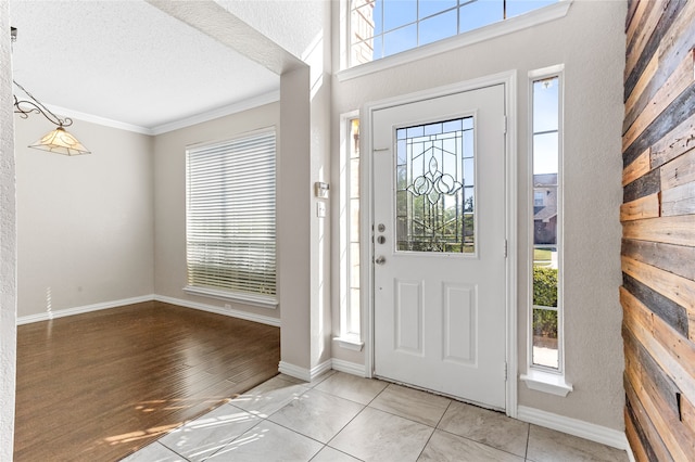 entryway with a textured ceiling, a wealth of natural light, light wood-type flooring, and ornamental molding