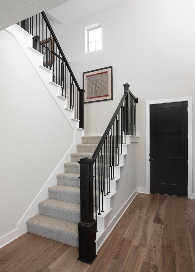 stairway with a towering ceiling and hardwood / wood-style floors