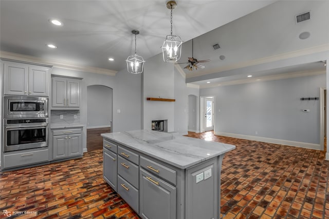 kitchen with a kitchen island, ornamental molding, a fireplace, gray cabinetry, and stainless steel appliances