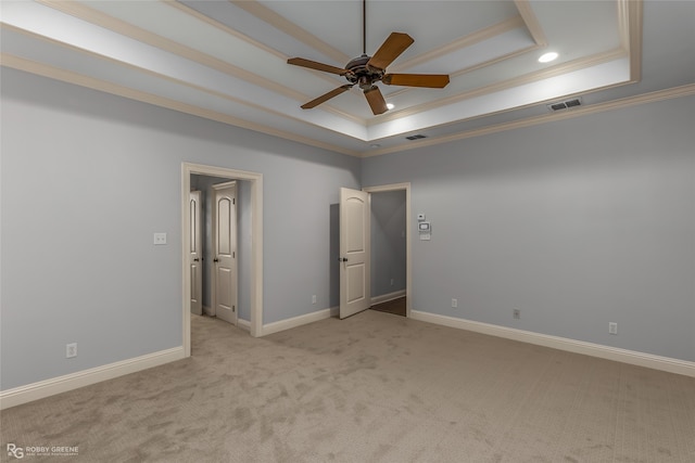 unfurnished bedroom with ceiling fan, crown molding, a tray ceiling, and light colored carpet