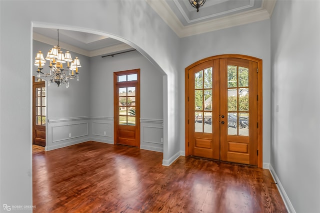 entrance foyer with french doors, dark hardwood / wood-style floors, a raised ceiling, and a wealth of natural light