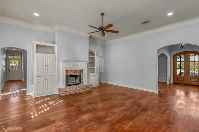 unfurnished living room featuring hardwood / wood-style flooring, ornamental molding, a wealth of natural light, and a fireplace