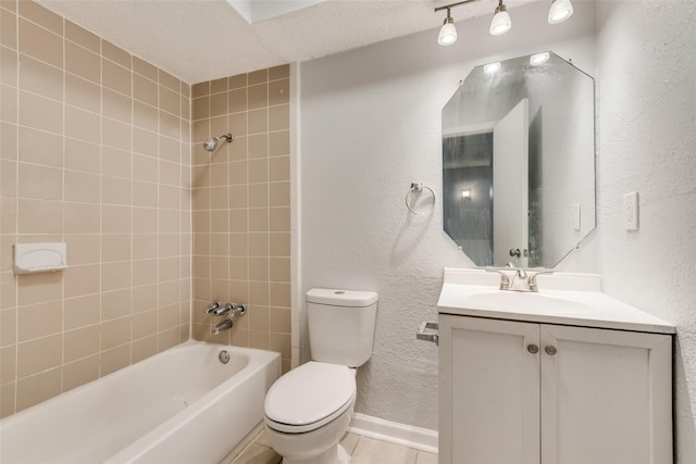 full bathroom featuring toilet, tile patterned flooring, tiled shower / bath combo, vanity, and a textured ceiling