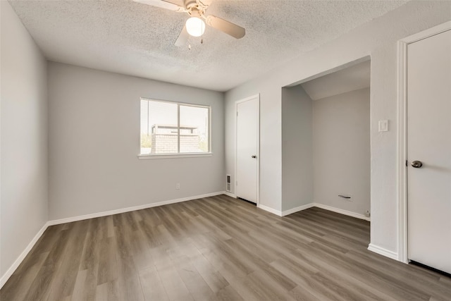 unfurnished bedroom featuring a textured ceiling, wood-type flooring, and ceiling fan