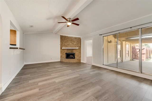 unfurnished living room with ceiling fan, hardwood / wood-style flooring, vaulted ceiling with beams, and a fireplace