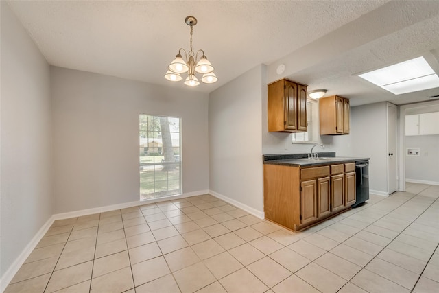 kitchen with black dishwasher, an inviting chandelier, a textured ceiling, light tile patterned flooring, and pendant lighting