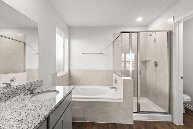 full bathroom with vanity, hardwood / wood-style floors, independent shower and bath, and toilet