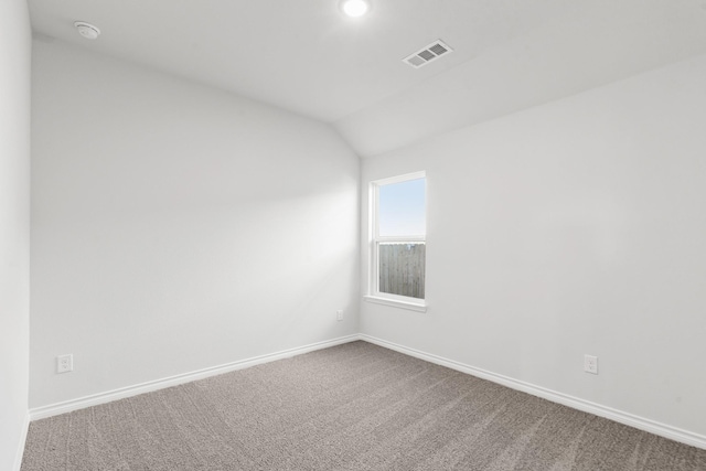 carpeted empty room featuring lofted ceiling