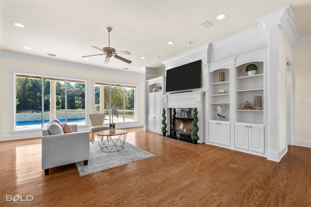 living room featuring crown molding, a fireplace, wood-type flooring, and plenty of natural light