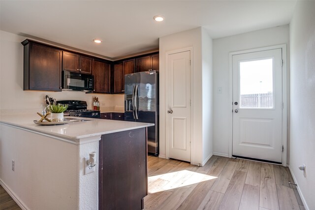 kitchen featuring dark brown cabinetry, stainless steel fridge, light hardwood / wood-style flooring, and stove