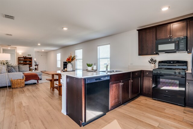 kitchen with sink, light hardwood / wood-style flooring, kitchen peninsula, and black appliances