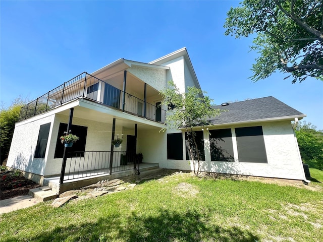 rear view of house with a yard and a balcony